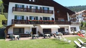 A multi-story building with balconies, outdoor seating, and a restaurant area. - Albergo Somont (Ortisei)
