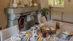 Ein Esszimmer mit Kamin aus Stein, einer Kristallleuchter und einem Tisch, gedeckt für das Frühstück.
