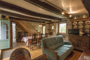 A rustic interior with a stone fireplace, wooden staircase, and a dining area with a table and chairs. - ty dreux (Saint-Thegonnec Loc-Eguiner)