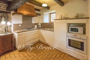 Compact kitchen with a herringbone-patterned tile floor, white gas stove, microwave, and double oven unit.