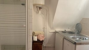 Une cuisine compacte dotée d’une cuisinière intégrée, d’un évier et d’un dosseret de carrelage blanc.