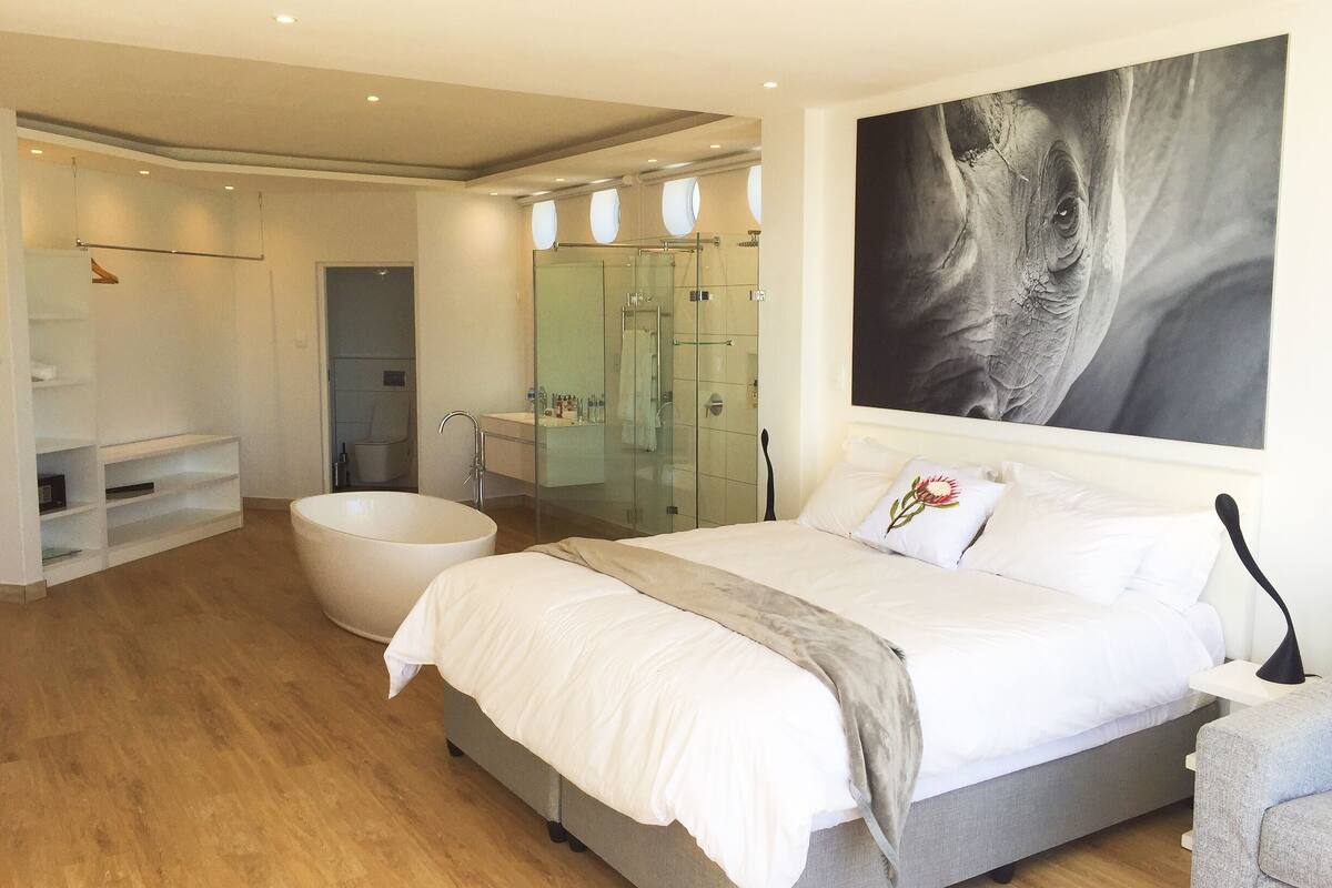 Un dormitorio moderno con una cama grande, una bañera y cabina de ducha.