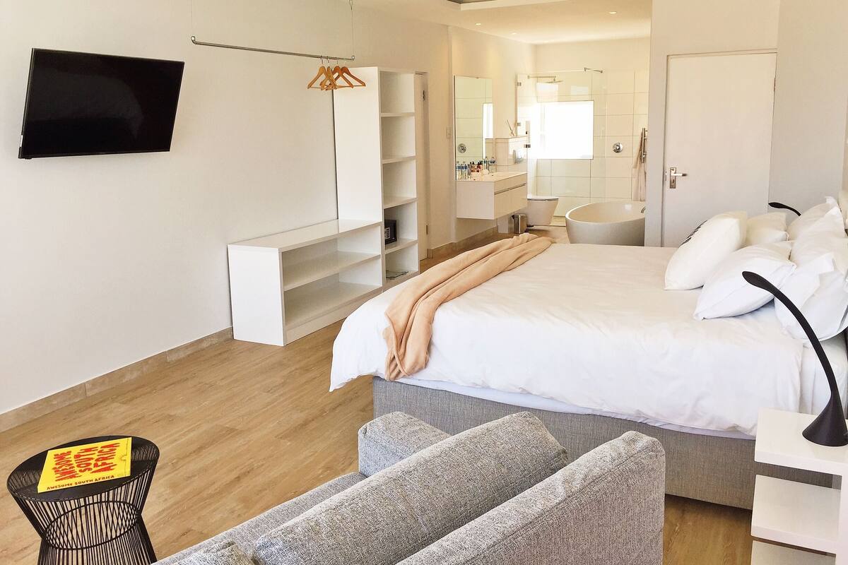 Un dormitorio moderno con una cama, mesita de noche y televisor montado en la pared.