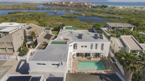 A residential area with modern houses, a swimming pool, and a view of the ocean and mountains. - Peach on Beach Boutique Guesthouse (Cape Town)
