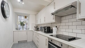 Une cuisine moderne avec des meubles blancs, une cuisinière noire et une fenêtre ornée de fleurs.