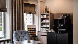 Une chambre d’hôtel avec un coin salon, une machine à café et une vue sur la ville.