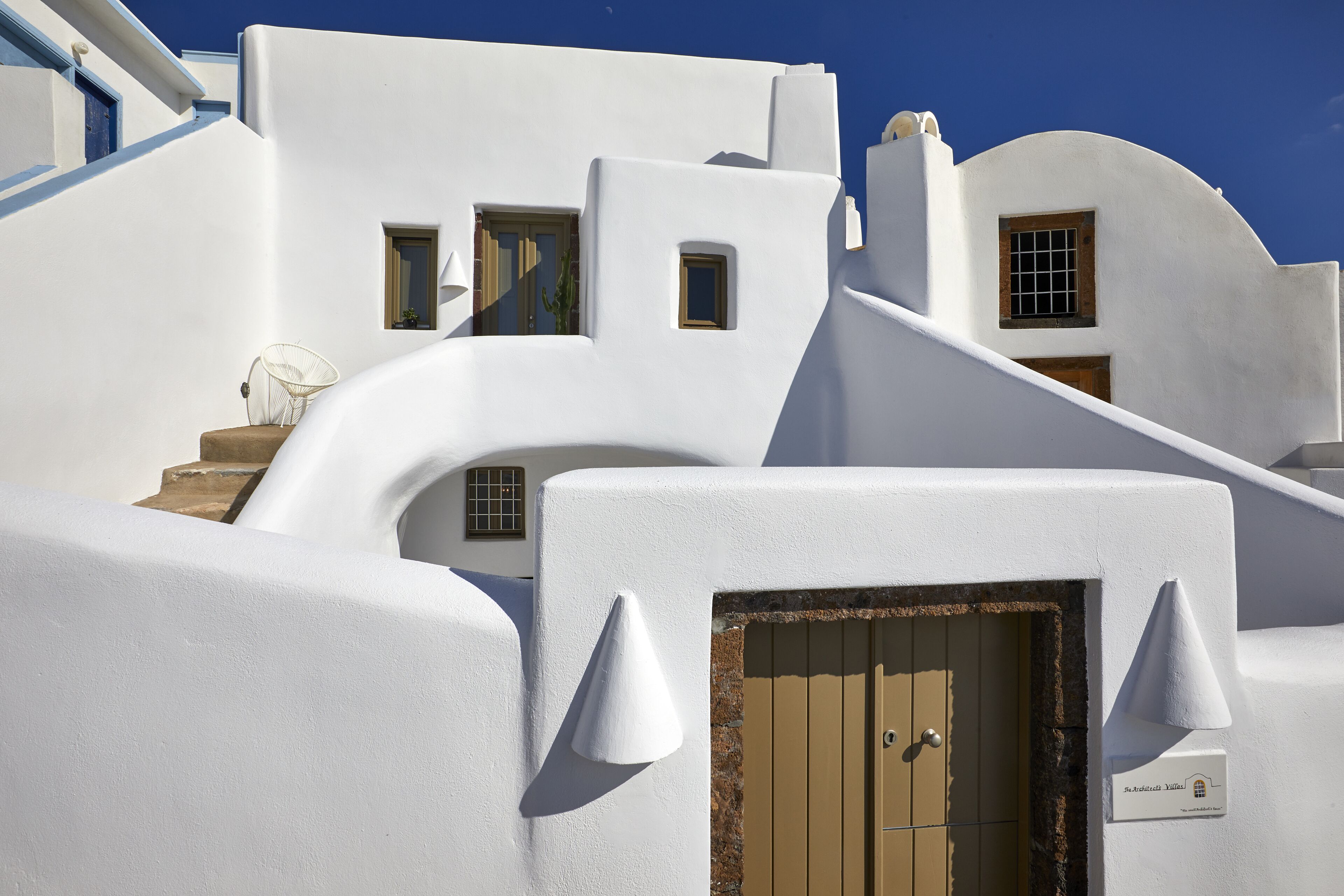 Un bâtiment blanc avec une porte marron et une petite fenêtre.