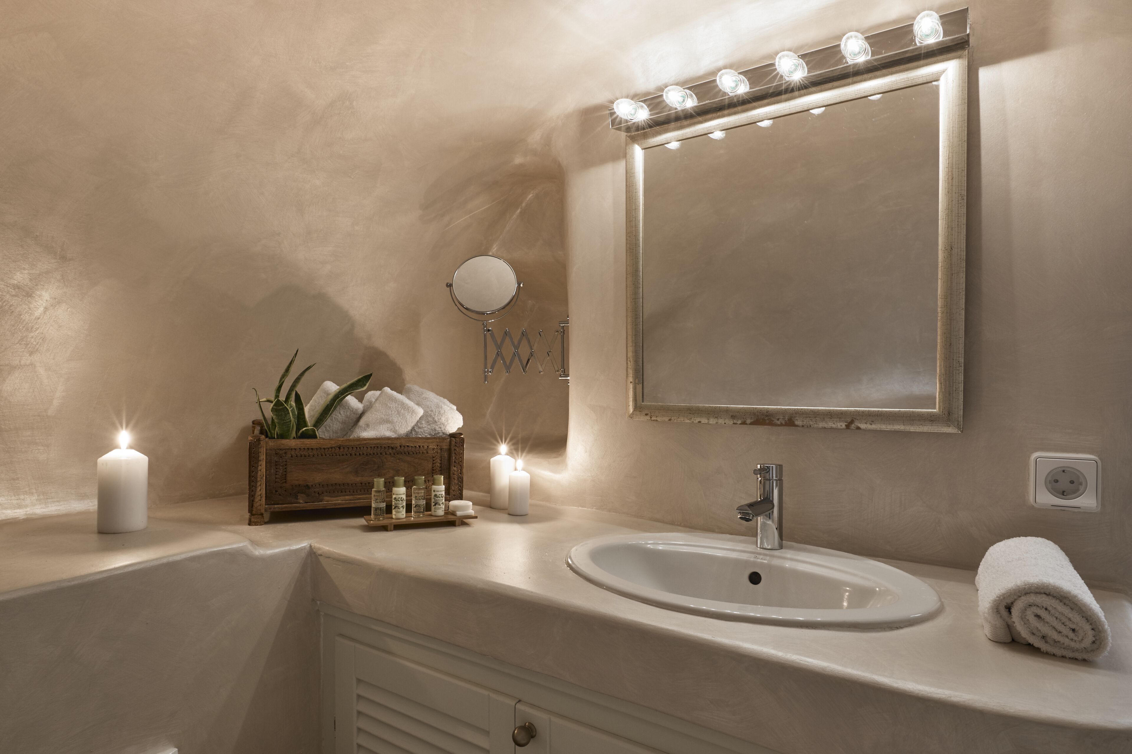 Une salle de bain avec un meuble-lavabo, un évier, un miroir et des bougies.