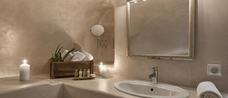 Une salle de bain avec un meuble-lavabo, un évier, un miroir et des bougies.