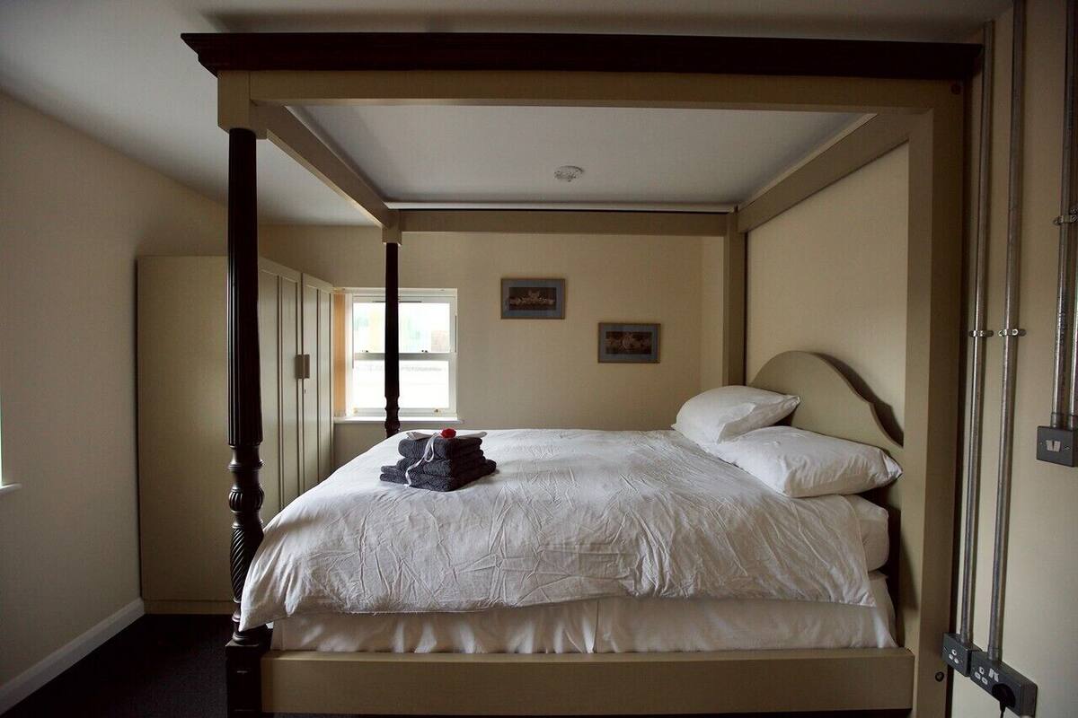 A bedroom with a large bed, a wooden headboard, a window, and a door.