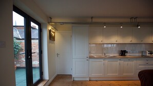 A modern kitchen with white cabinets, a large window, and a wooden floor. - No1 Dove Street (Ipswich)