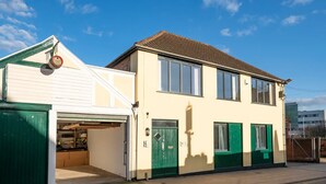 A two-story building with a garage, green doors, and a tiled roof. - No1 Dove Street (Ipswich)