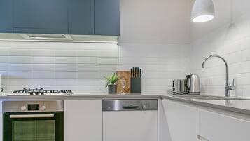 Una cocina moderna con armarios blancos, un lavavajillas Bosch, una estufa a gas y un tostador de acero inoxidable.