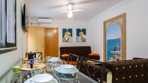 Un comedor con una mesa de vidrio, sillas y vista al mar a través de una ventana.