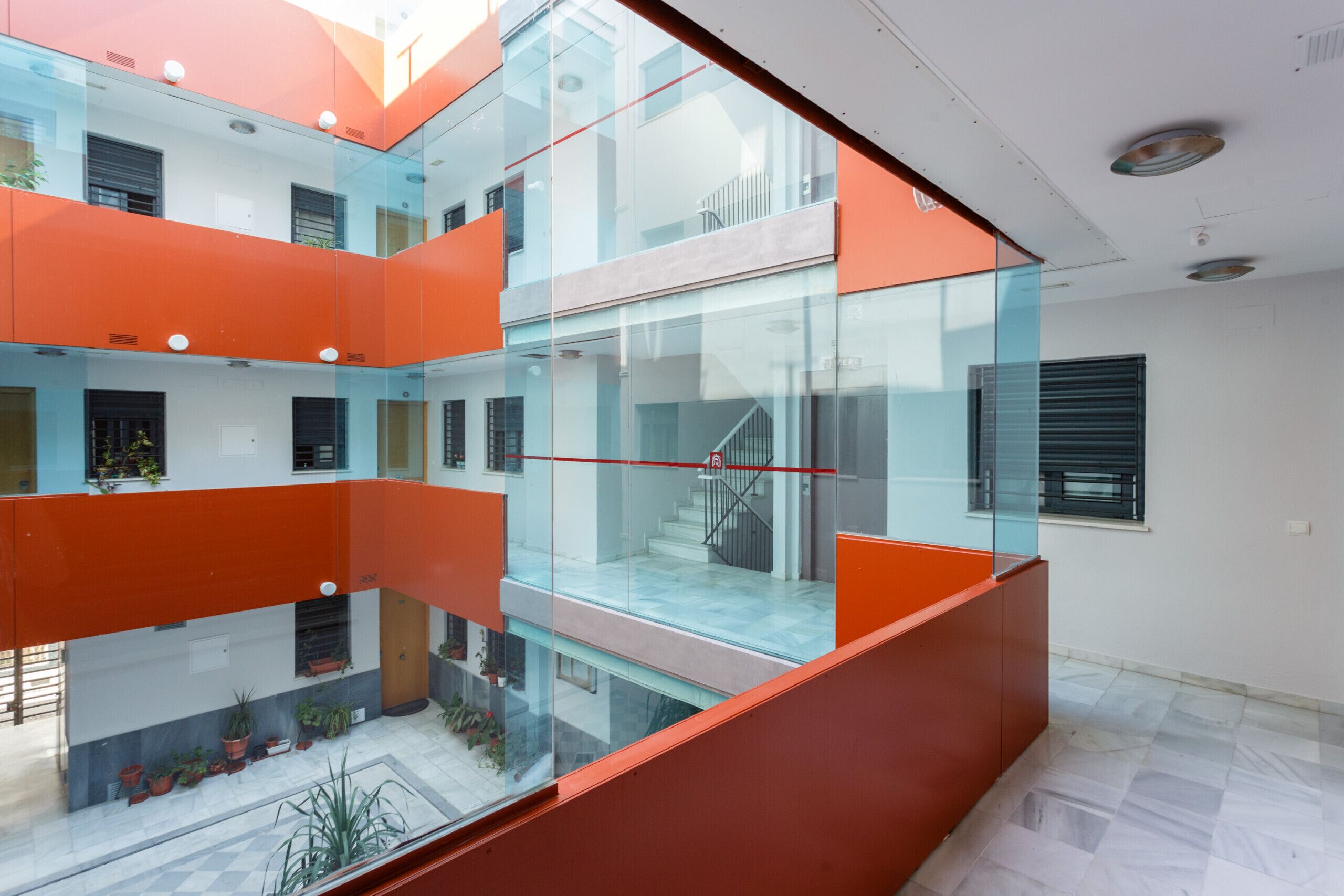 A modern building with glass balconies and orange accents.
