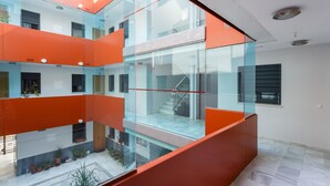 Un edificio moderno con balcones de vidrio y detalles en naranja.