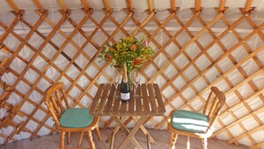 A wooden table with two chairs, a bottle of champagne, and a vase of flowers in a tent-like structure. - Les Yourtes d'Agnac (Agnac)