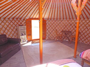 A cozy room with a wooden lattice wall, a bookshelf, a cushioned sofa, and a small table.