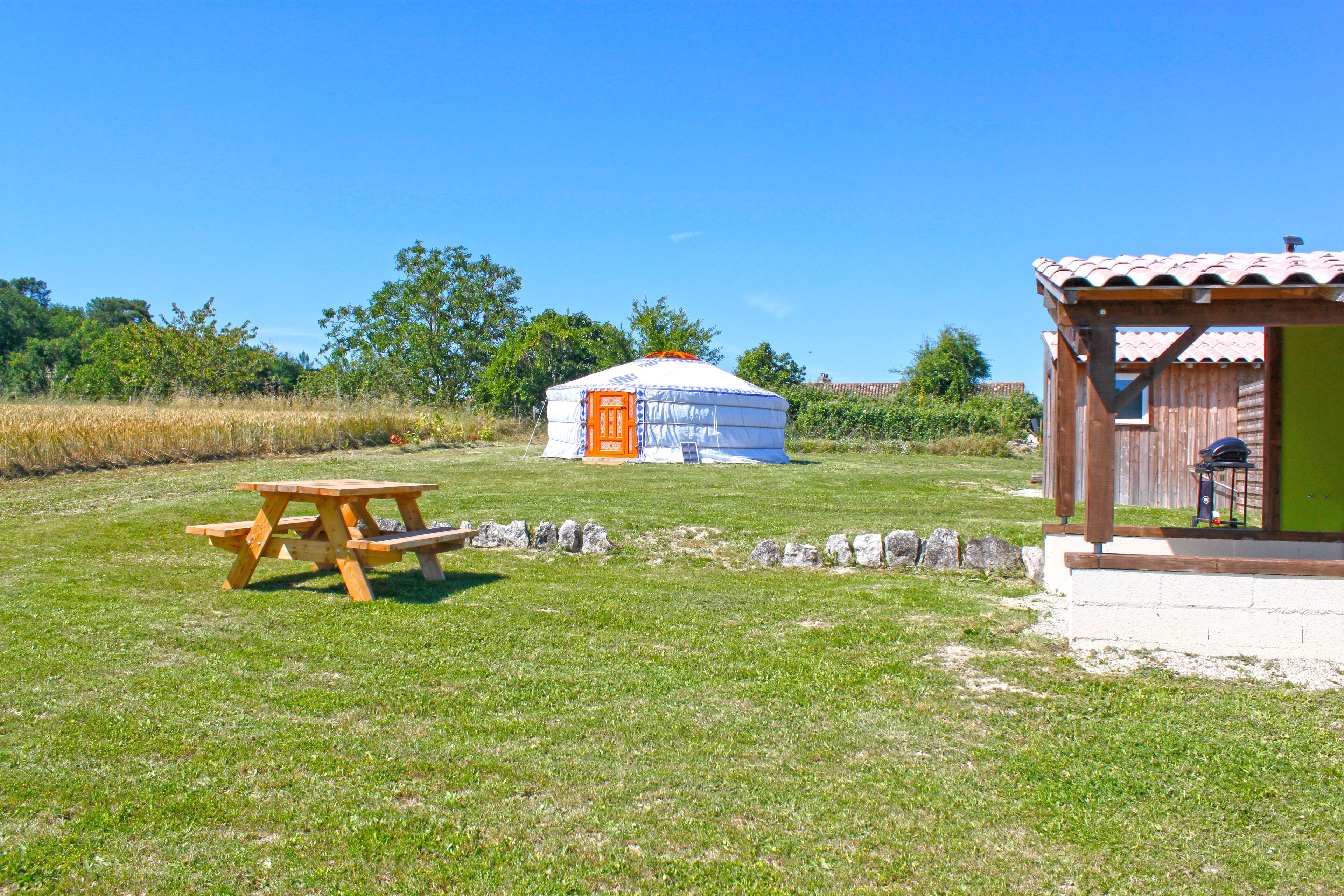A yurt with a picnic table in a grassy field.