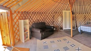 A room with a bed, a chair, a small table, and a wardrobe. - Les Yourtes d'Agnac (Agnac)