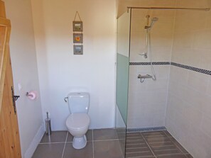 Une salle de bain comprenant des toilettes, un espace de douche vitré et un cadre photo fixé au mur.