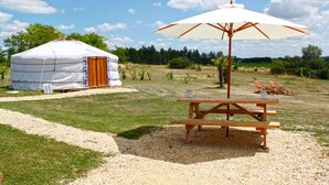 A yurt with a picnic table and umbrella in a grassy field. - Les Yourtes d'Agnac (Agnac)