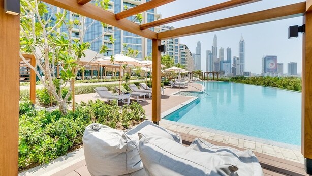 Área da piscina com espreguiçadeiras e guarda-sóis, com vista para o horizonte urbano.