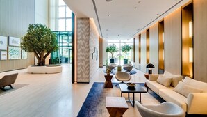 Um lobby moderno com uma grande árvore, área de estar e balcão de recepção.