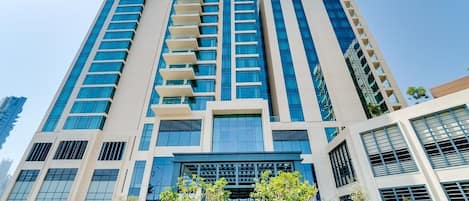 A modern high-rise building with multiple floors, large windows, and a central entrance.