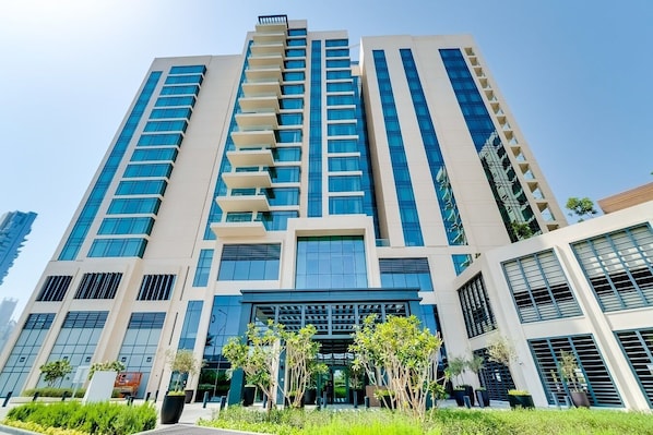 A modern high-rise building with multiple floors, large windows, and a central entrance.