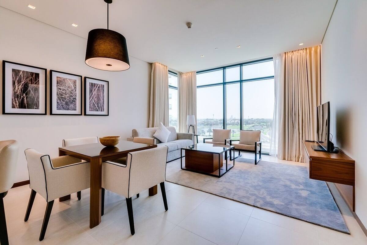A modern living room with a dining area, large windows, and a view of the cityscape.