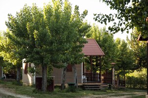 Una pequeña cabaña con porche, rodeada de árboles.