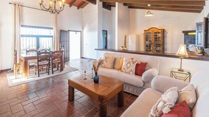 A spacious living area with a wooden coffee table, a sofa, and a dining table with chairs. - El Encinar Antequera - La Joya by Ruralidays (Málaga)