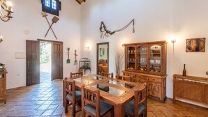 Un coin repas avec une table et des chaises en bois, un meuble avec des portes en verre et une décoration rustique comprenant un luminaire suspendu et des objets fixés au mur.