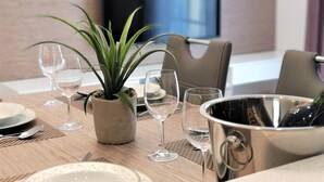 Una mesa de comedor dispuesta con platos, copas de vino, una planta en maceta y un enfriador de champán.