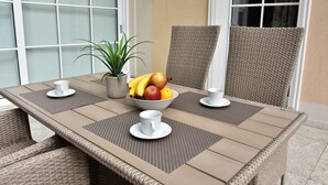 Una mesa de comedor con un frutero, dos tazas blancas y una planta en maceta.