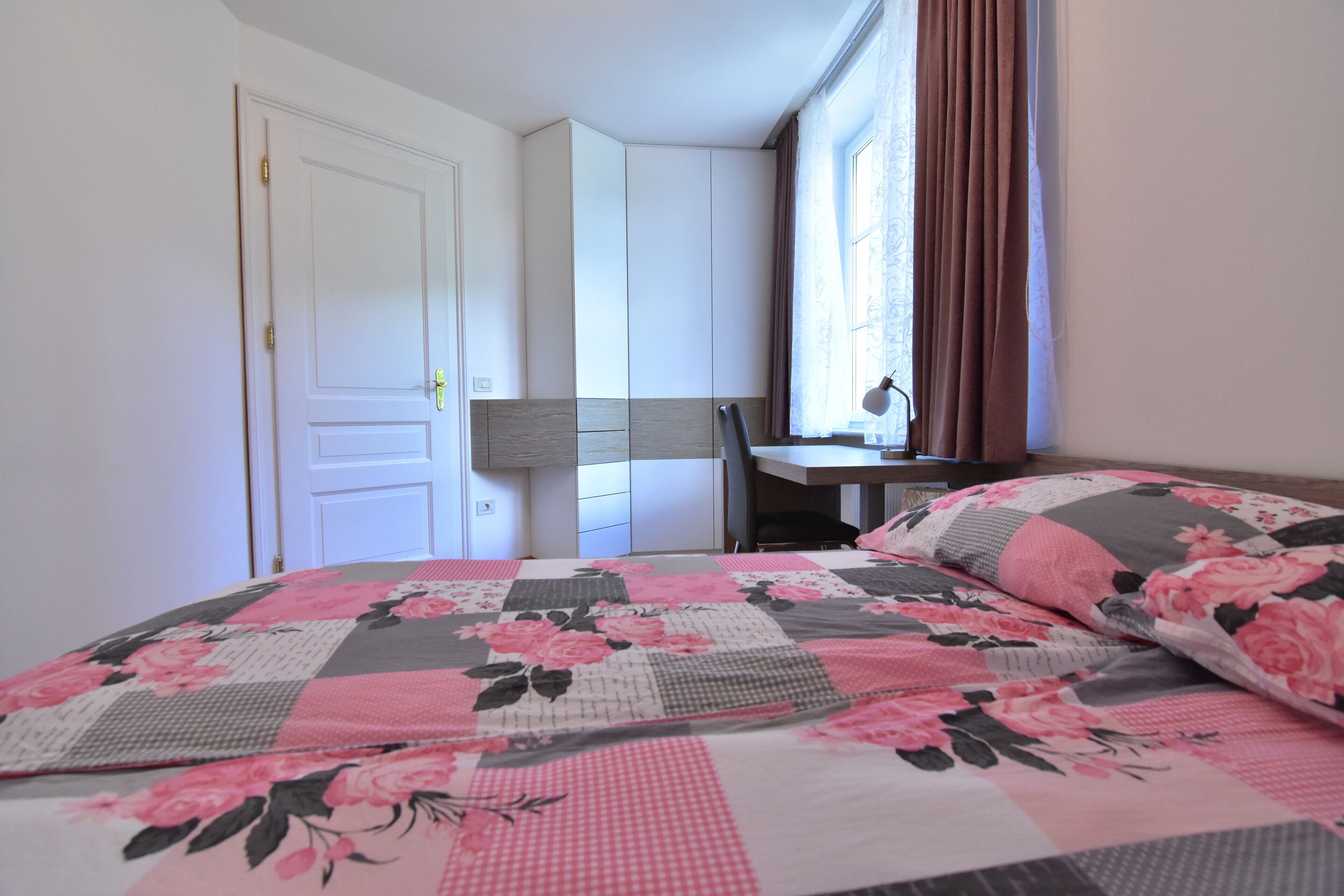 A bedroom with a bed, a desk, and a chair.