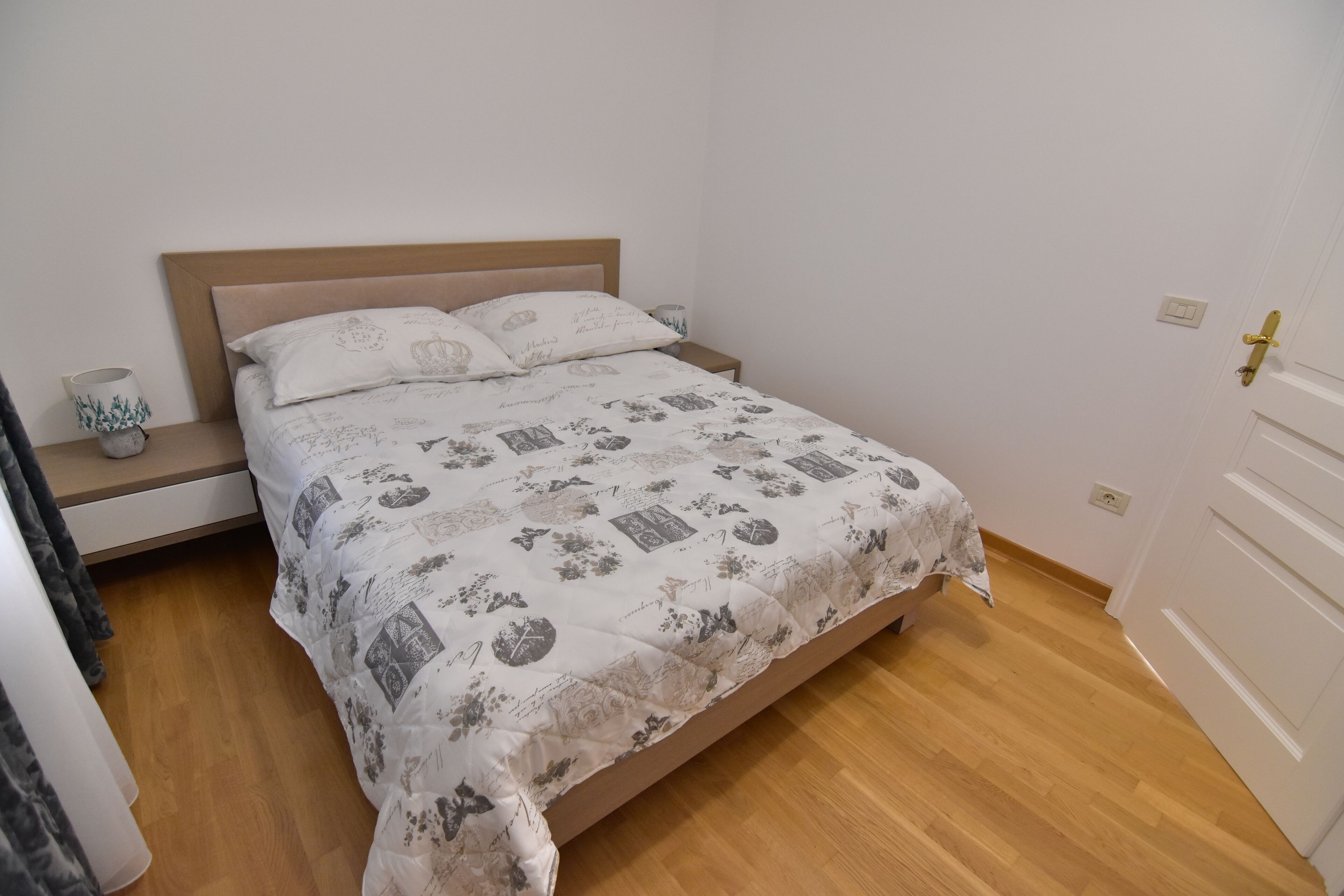 A bedroom with a bed, bedside tables, and a door.