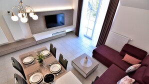 Una sala moderna con televisor, comedor y sofá.