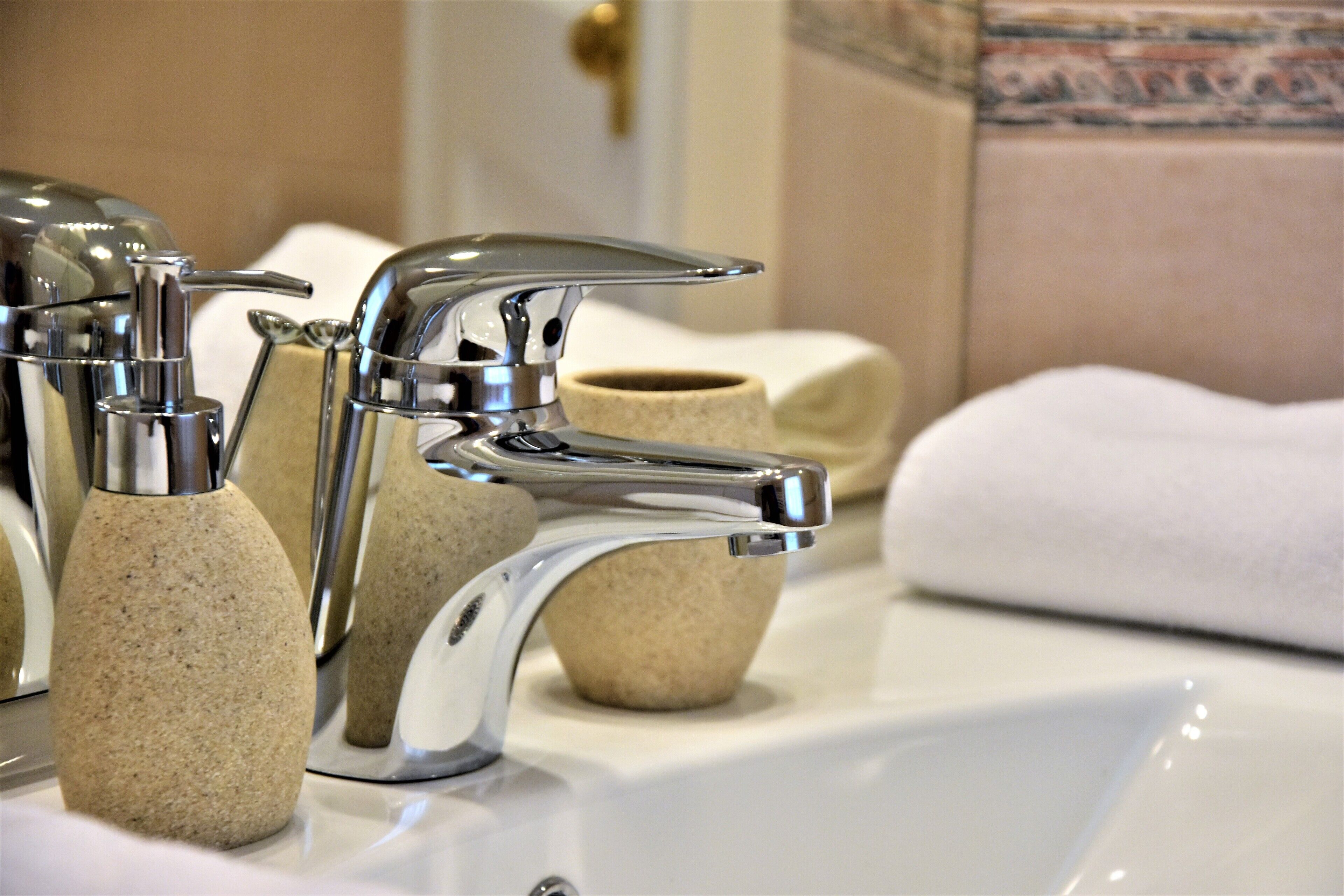 A bathroom with a modern faucet, a soap dispenser, and a towel.