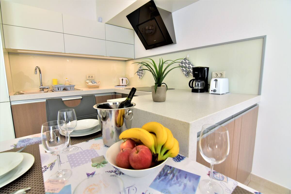 Een moderne keuken met een eethoek, inclusief een tafel gedekt met borden, glazen en een schaal fruit.