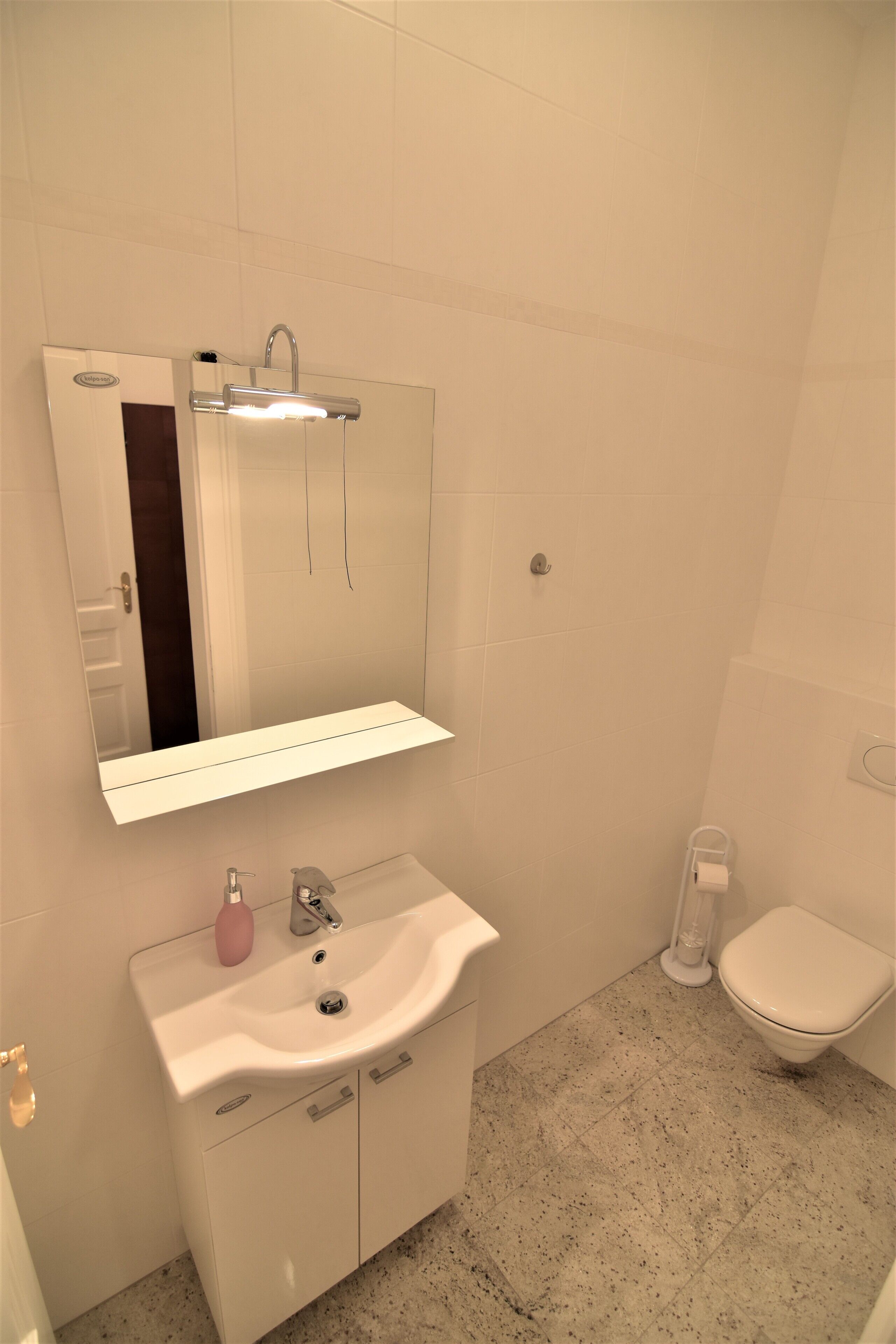 A bathroom with a white sink, mirror, and toilet.