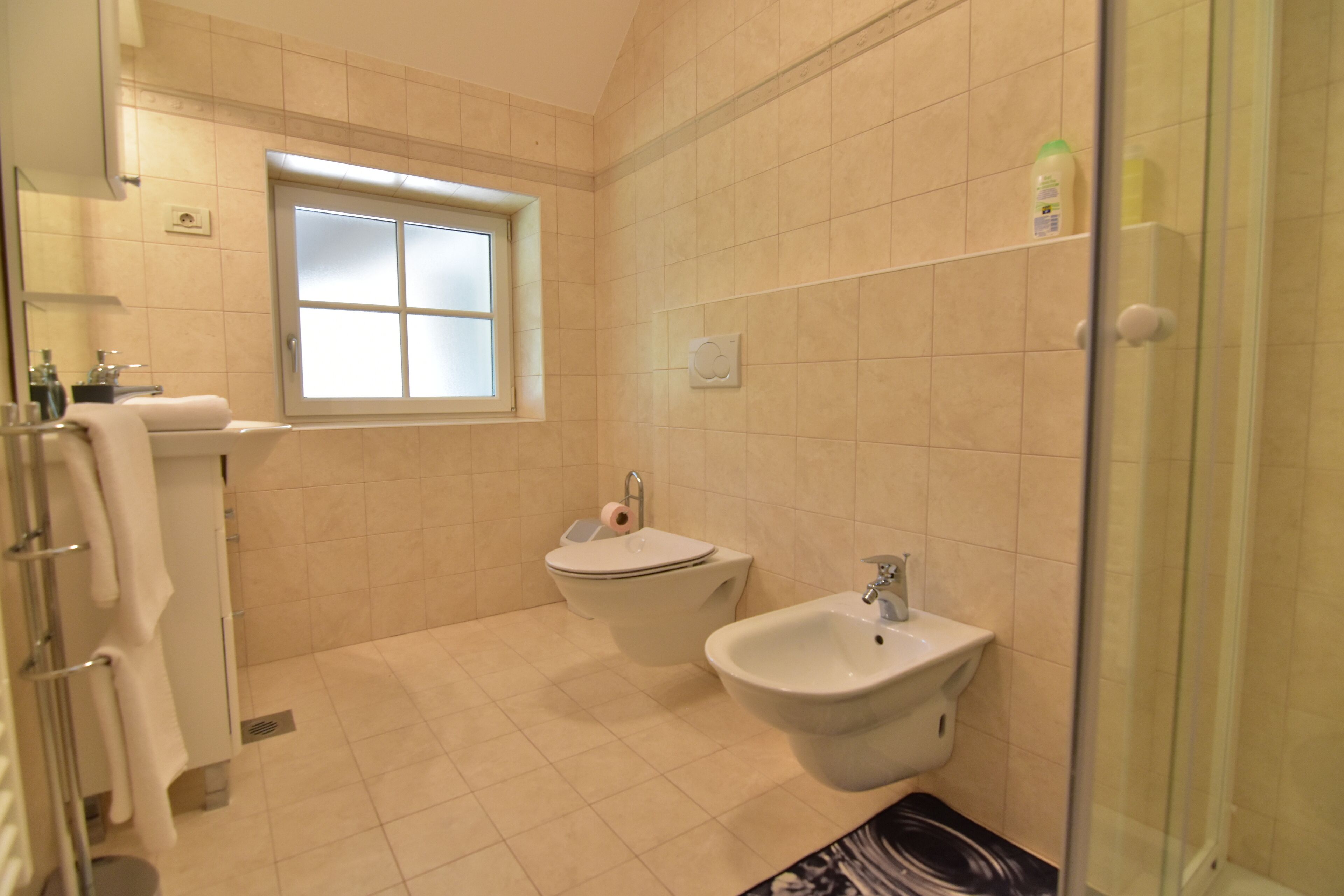 Une salle de bain équipée de toilettes, d’un bidet et d’un lavabo.