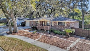 A single-story house with a front porch, a brick exterior, and a well-maintained lawn. - Shady Oaks - Breezy retreat w patio & beach access (Jacksonville Beach)