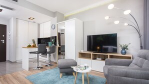 A modern living room with a TV, grey sofas, a small table, and a kitchen area in the background. - Studio Apartment, 15 min. walk to Main Square, 10 min. walk to Jewish Quarter (Grzegórzki)