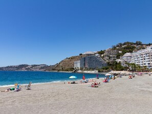 A beach with a clear blue sky, sandy shore, and buildings in the background. - Apto Jardines de Mariote. Appartment in San Cristobal beach with wifi. (Almuñécar)