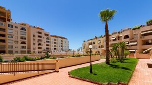 A courtyard with a palm tree, tiled flooring, and a fence.
