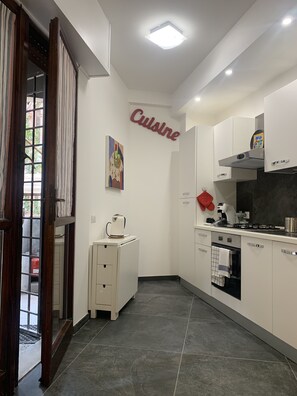 Une cuisine moderne avec des meubles blancs, une cuisinière et une machine à café.