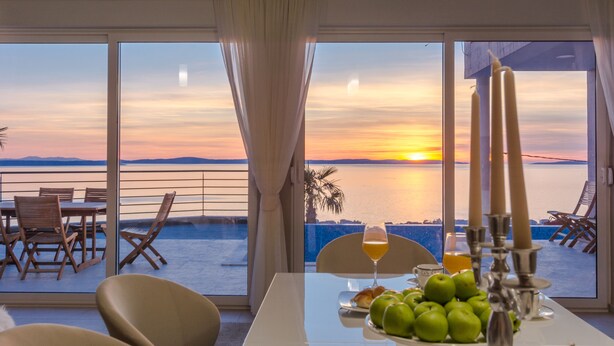 A dining area with a table set for two, overlooking a scenic sunset view.