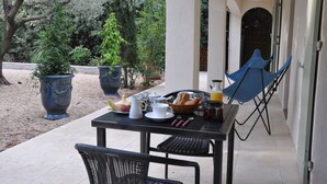 A breakfast setup with a table, chairs, and potted plants. - Chambres D'hôtes Sous L'olivier (Montpellier)